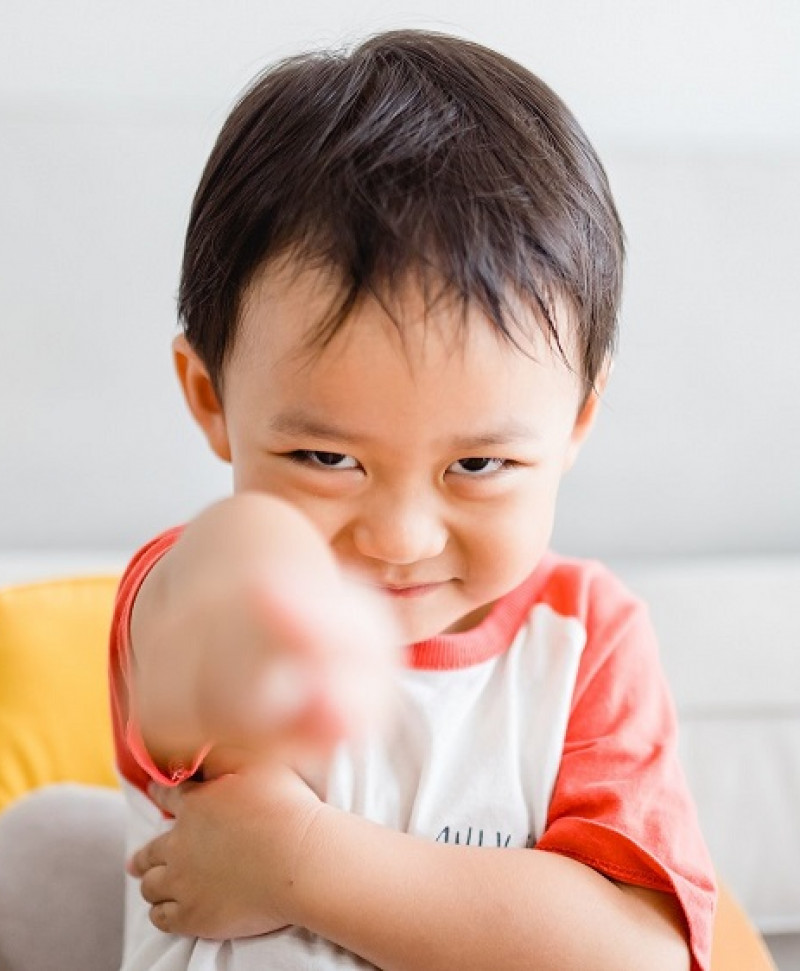 Little boy pointing directly at the camera with a cheeky grin